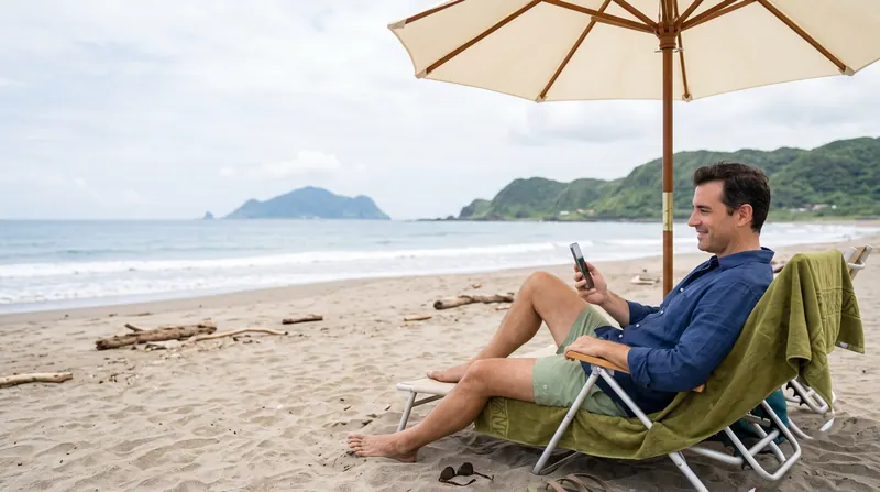 Una persona tumbada en una silla bajo una sombrilla en la playa, mirando el teléfono